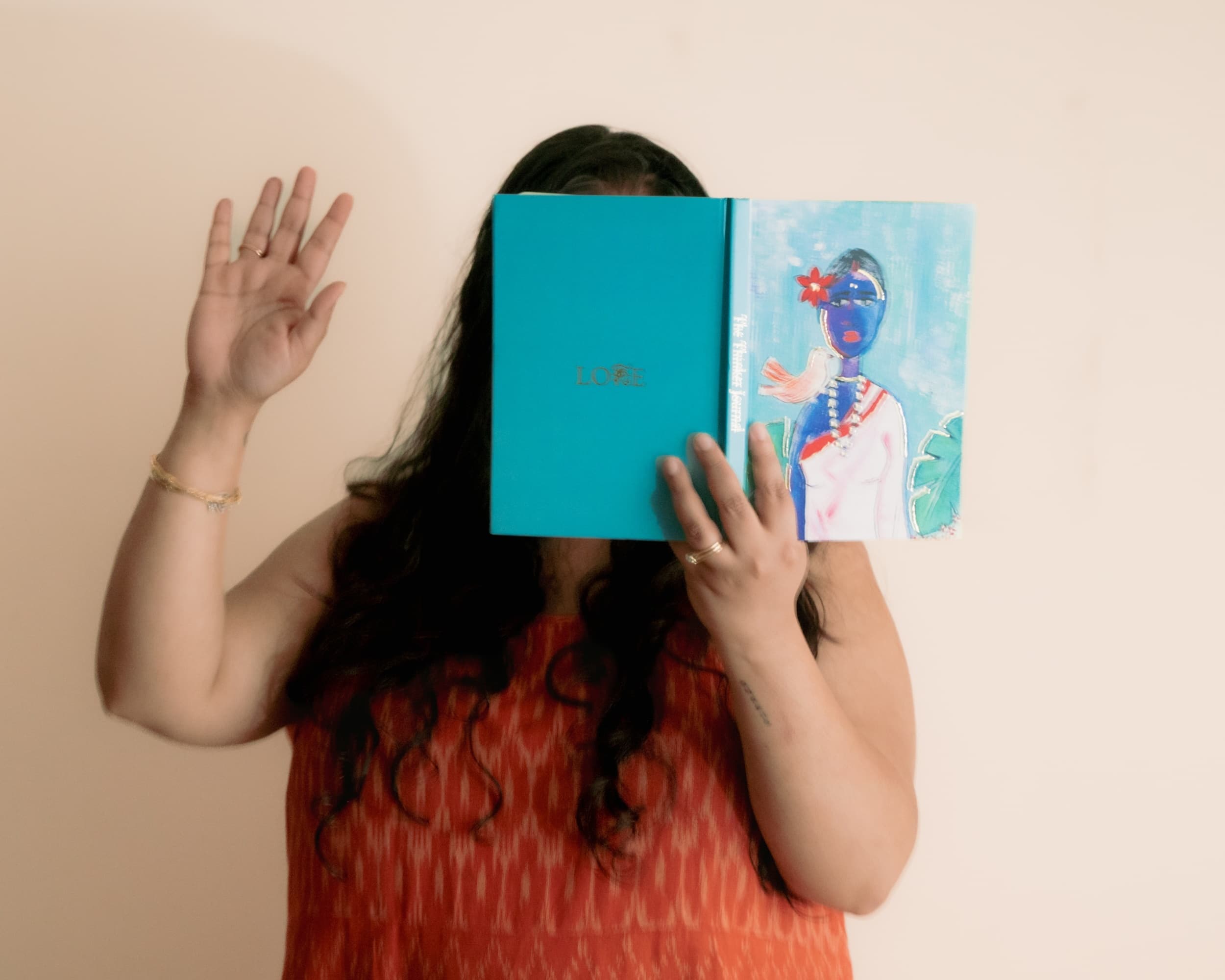 A woman holding an open illustrated journal in front of her face