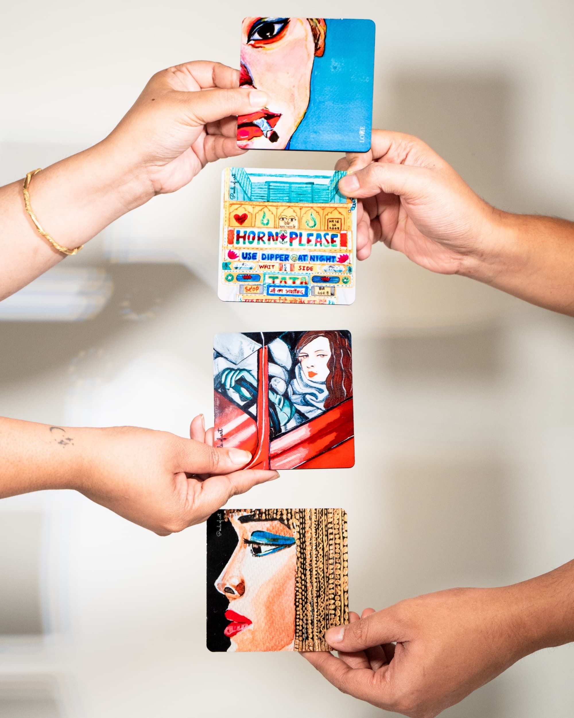 A hand holding an illustrated bookmark against a red envelope on a wooden table