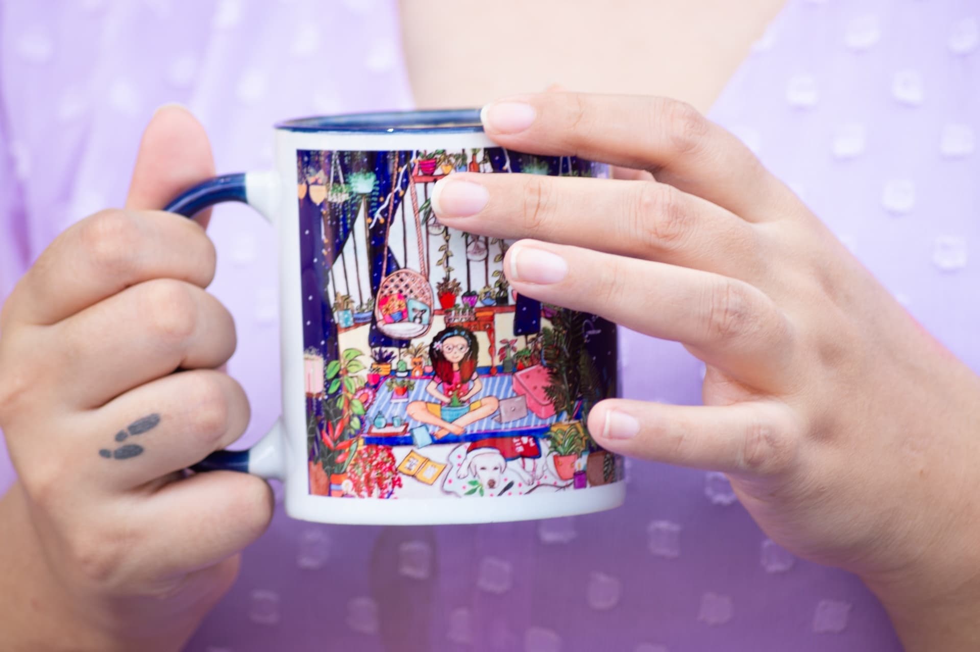 Hands holding an illustrated mug printed with a girl sitting among houseplants and a dog