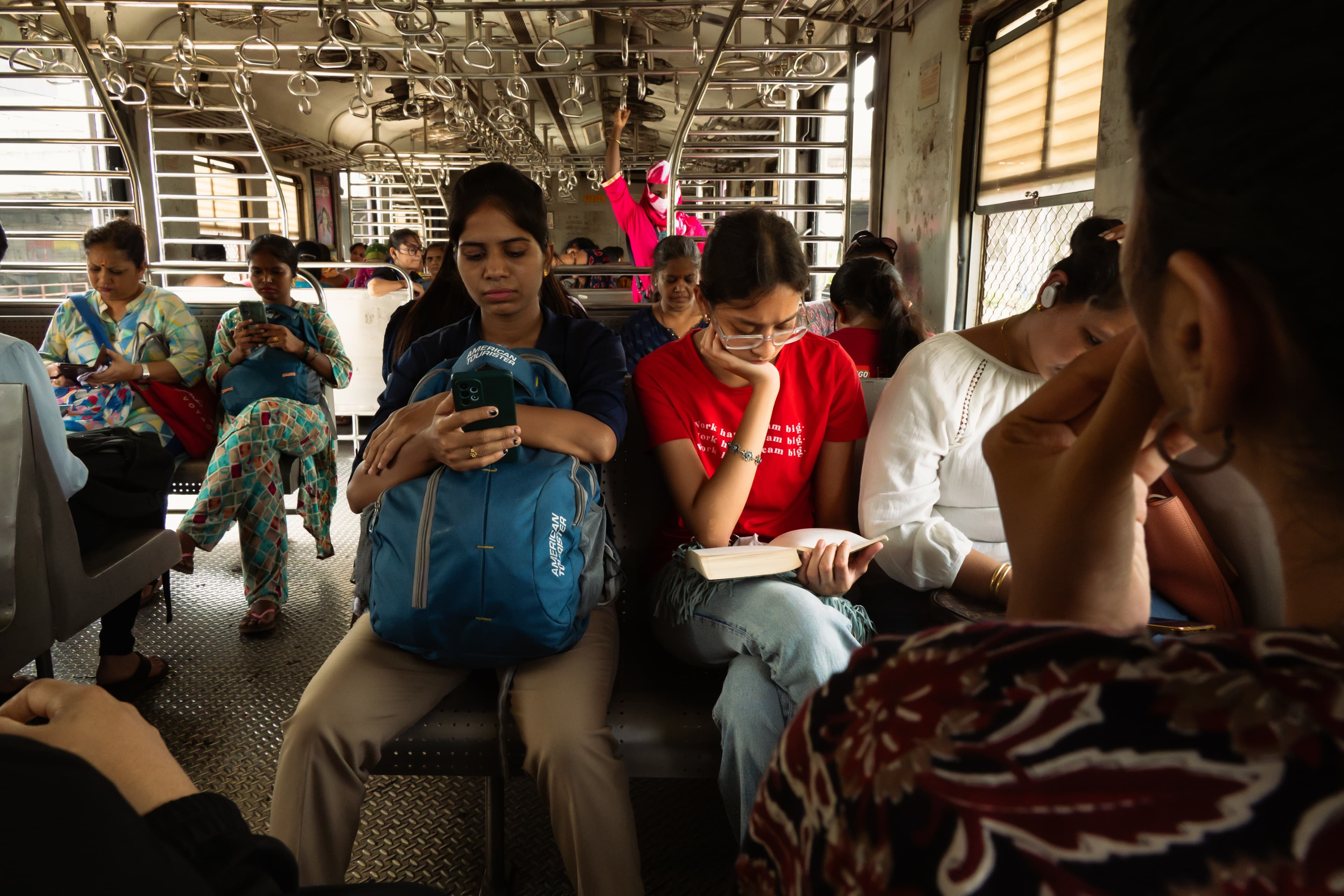 Commuters reading books and phones inside a crowded Mumbai local train